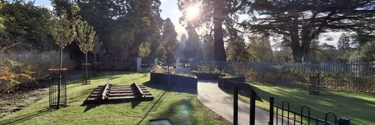 The memorial garden beside Brookwood station, with a short length of old track set into the lawn and low autumn sun through the trees